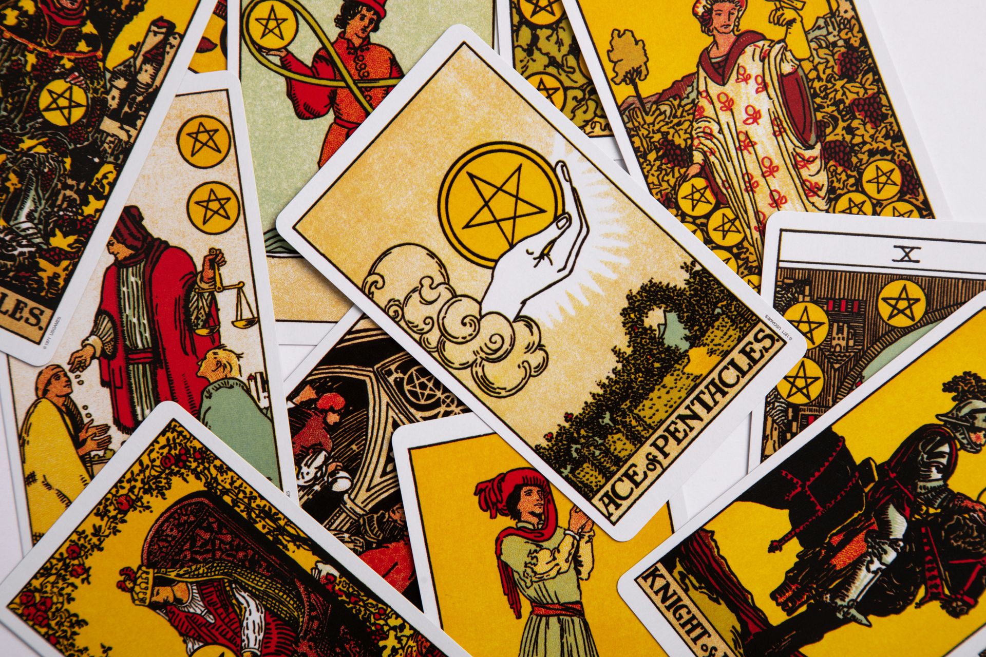A collection of colorful tarot cards featuring the Ace of Pentacles prominently displayed