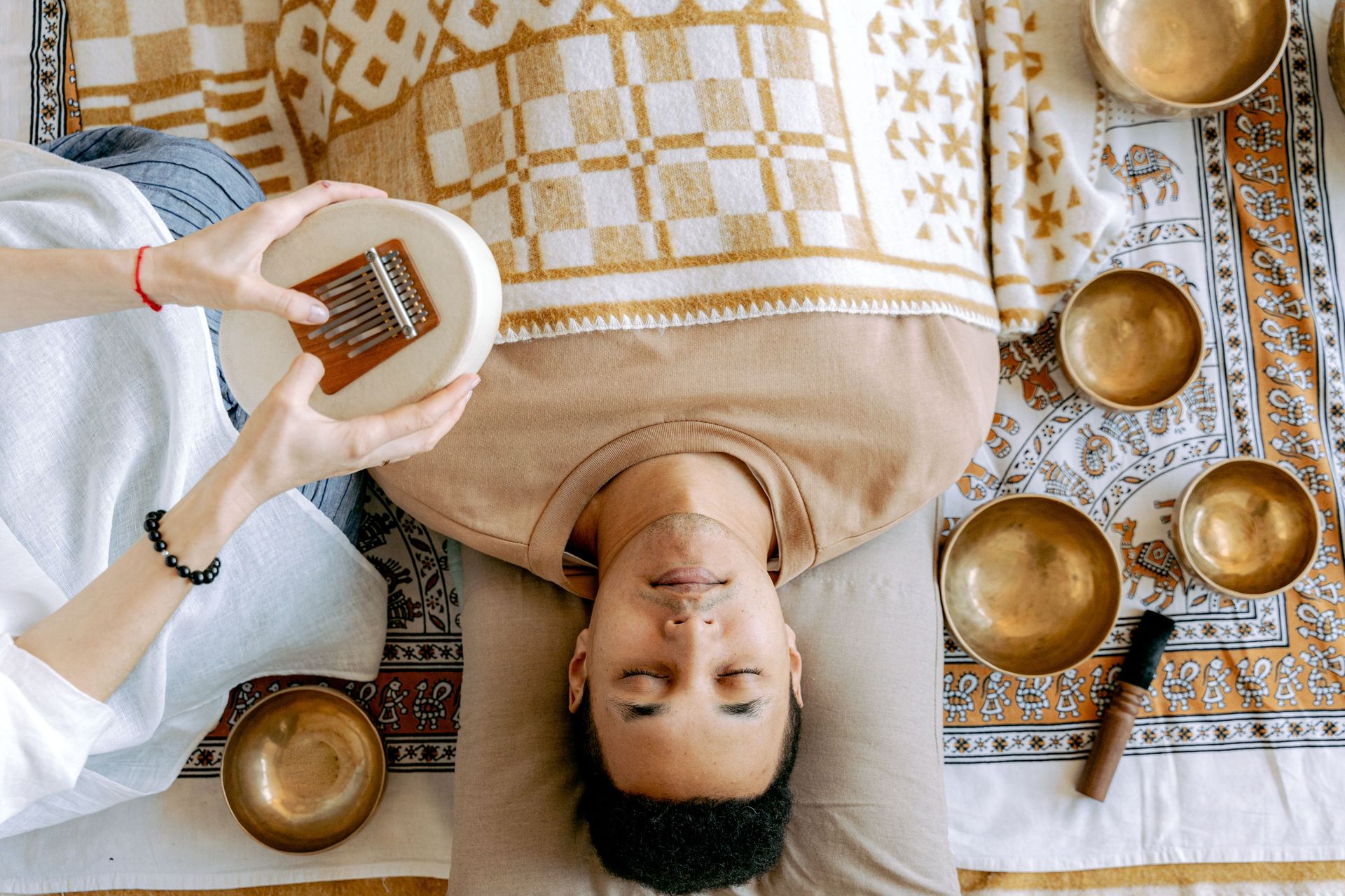 A serene sound bath session featuring a man relaxing with a kalimba and singing bowls.
